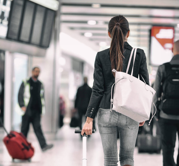 Travel background airport terminal passengers walking in lounge. Asian woman walking from behind with purse carrying luggages for delayed flights to vacation holidays - Photo, Image