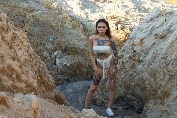 Азиатская девушка с татуировкой в белом бикини позирует в горах - Фото, изображение