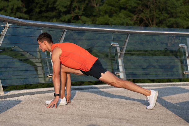 Αθλητής κρατήσει lunge θέση κάνει τέντωμα ρουτίνας μετά από εξωτερική αθλητική προπόνηση, τέντωμα - Φωτογραφία, εικόνα