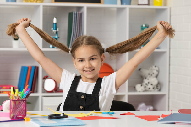 criança feliz se divertindo com cauda de pônei de cabelo longo na lição da escola em sala de aula usar uniforme, escola - Foto, Imagem