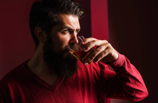 Degustáció, kóstolás. Szakállas férfi egy pohár whiskyvel. Férfi konyakot vagy konyakot iszik. Drága ital.. - Fotó, kép