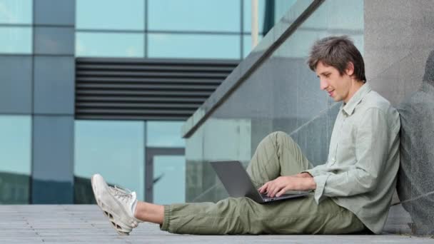 Millennial guy snel energiek typen artikel, rapport of bericht op laptop toetsenbord, jonge volwassen man tevreden met zaadgoed, succesvol productief werk, glimlacht, steekt duim omhoog, toont ok gebaar - Video