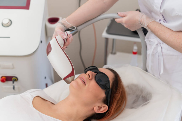 Close-up of laser hair removal on a womans face. The doctor removes unwanted hair from the patient above the lip with an electric device - Φωτογραφία, εικόνα
