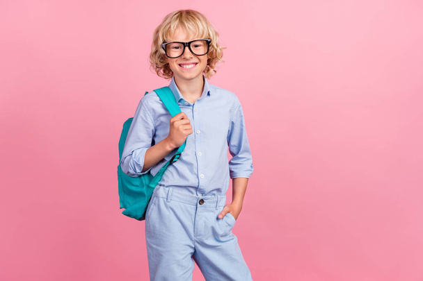 Photo of cool funny school boy wear blue shirt glasses backpack smiling empty space isolated pink color background - Foto, afbeelding
