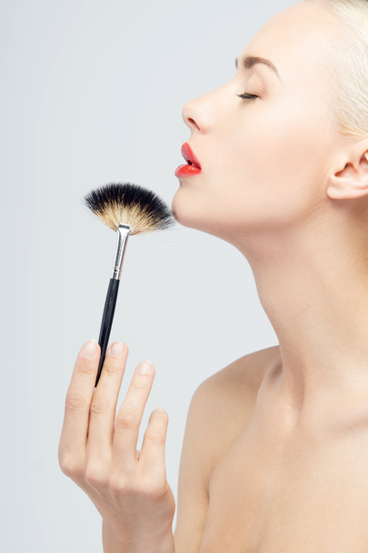 Beautiful Young Woman Applying Makeup with Brush - Foto, afbeelding