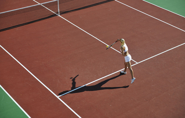 Young fit woman play tennis outdoor on orange tennis field at early morning - Photo, Image