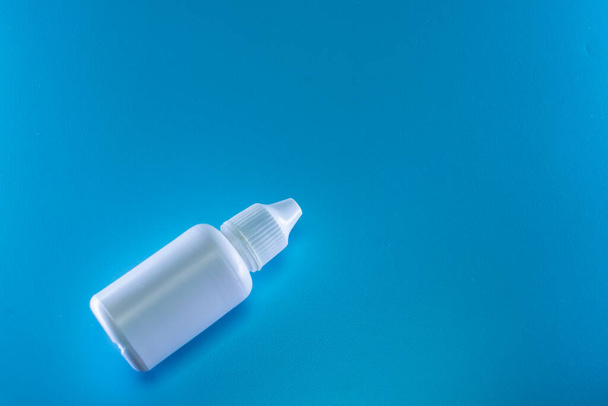 Bottle of white drops on a blue background - Foto, Imagem