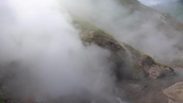 La erupción de un géiser. El agua hirviendo es expulsada de la caldera en corrientes potentes. El spray está volando. El vapor caliente espeso esconde las laderas de las montañas. Kamchatka. Valle de los Géiseres - Imágenes, Vídeo