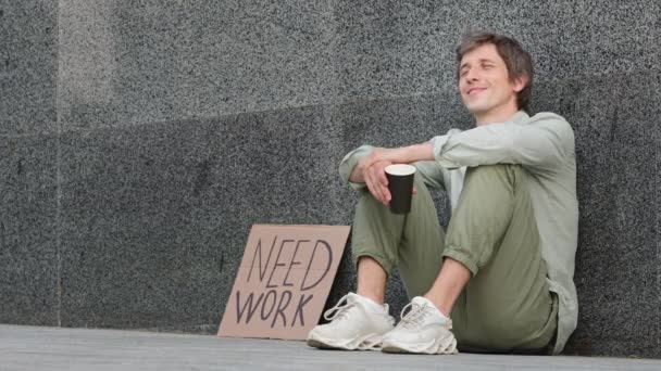 Millennial senzatetto, licenziato, lasciato senza soldi, in cerca di lavoro, pregando per l'elemosina, pronto ad accettare aiuto. Giovane uomo d'affari seduto all'aperto con segno bisogno di lavoro è andato in bancarotta - Filmati, video