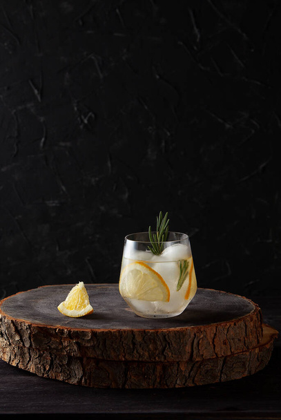 verfrissend drankje met citroenrozemarijn en ijs op donkere houten achtergrond - Foto, afbeelding