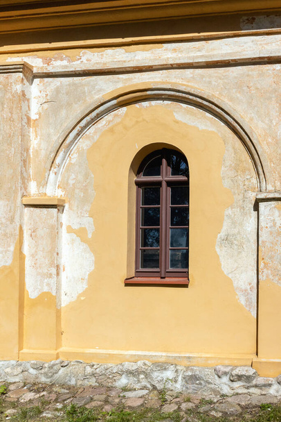 Una vieja ventana arqueada en una pared de arco enlucido amarillo que se desmorona - Foto, imagen