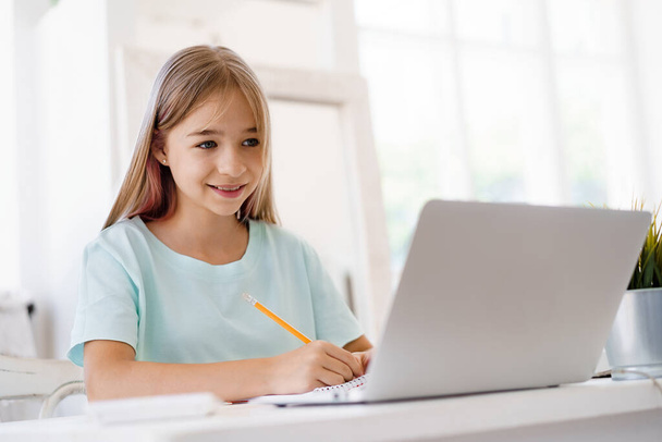Young girl using laptop for homework at home - Foto, Imagem