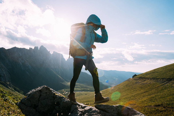 Successful woman backpacker hiking on sunset alpine mountain peak - Zdjęcie, obraz