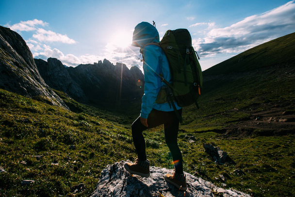 Successful woman backpacker hiking on sunset alpine mountain top - Foto, afbeelding