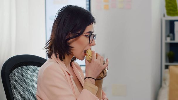 起業家の女性おいしいサンドイッチを食べることは、ビジネス会社で働く休憩を持っている - 写真・画像
