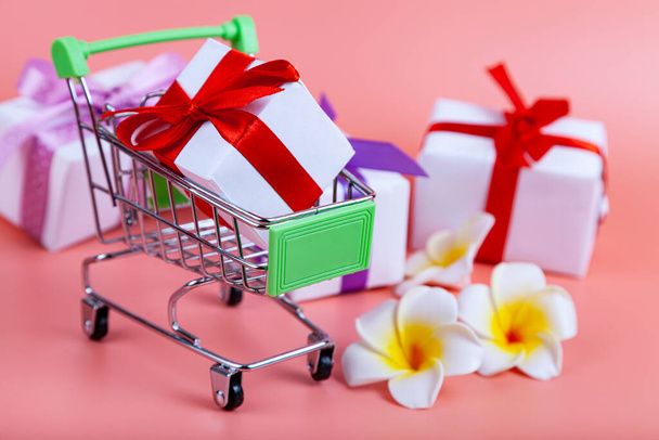Shopping cart and gifts on a pink background. Concept: buying gifts. - Foto, immagini