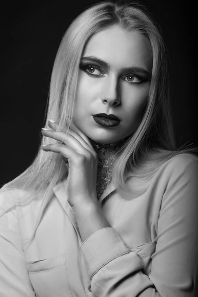 Alluring blond model posing at studio with bright makeup and foil on her neck. Monochrome shot - Foto, Imagen