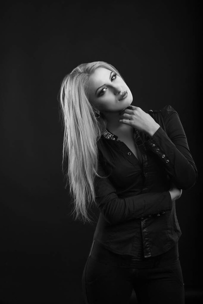 Stylish blond woman with perfect makeup and long straight hair wears blouse, posing at studio. Black and white shot - Foto, immagini