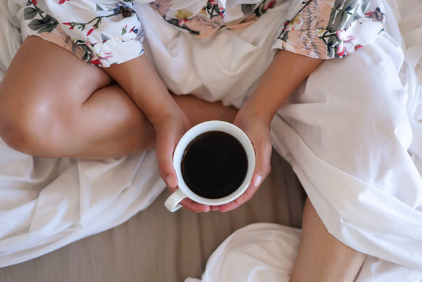 close up of young woman with cup of coffee in bed at home - Fotoğraf, Görsel