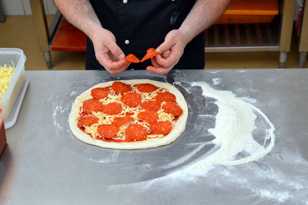 Der Prozess der Herstellung von Pizza, Nahaufnahme Hand des Chefs Bäcker macht Pizza in der Küche. - Foto, Bild