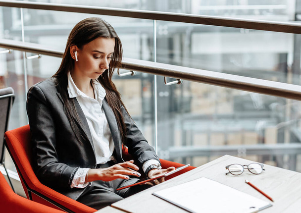 Businesswoman at her workplace reads information on a tablet. A woman works with documents and searches for insights on the Internet. The girl is thinking about the idea of a new startup in the office. - Foto, Bild