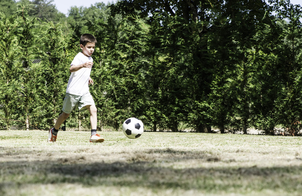 Child playing football in a stadium - Fotoğraf, Görsel