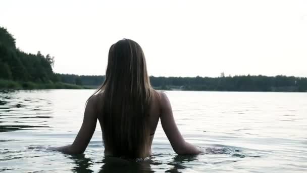 Siyah bikinili seksi, baştan çıkarıcı genç, ince kadın yavaşça göle yüzmek için giriyor. - Video, Çekim