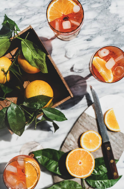 Aperol Spritz aperitif alcohol cold drink in glasses with oranges and ice cubes over grey marble table, top view. Summer refreshing drink concept - Foto, imagen