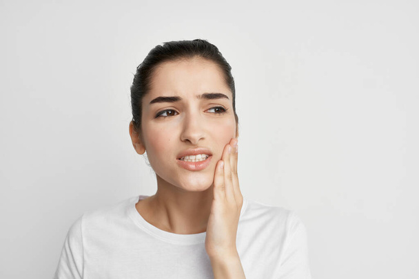 Frau im weißen T-Shirt mit Zahnarztbehandlung für Zahnschmerzen im Gesicht - Foto, Bild