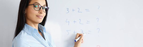 Woman teacher standing at blackboard with formulas and explaining information - Foto, Bild