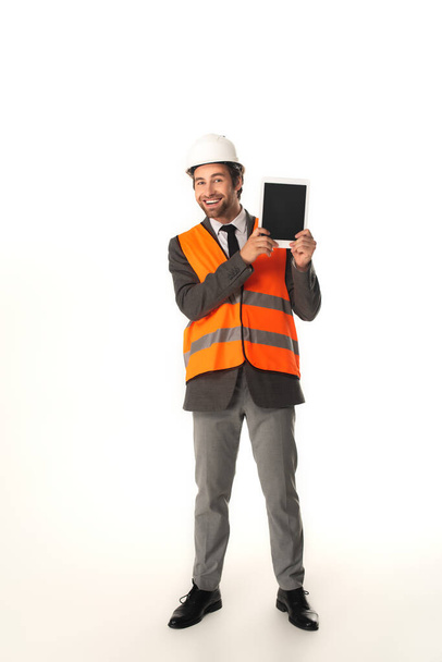 Full length of smiling engineer with digital tablet looking at camera on white background  - Foto, immagini