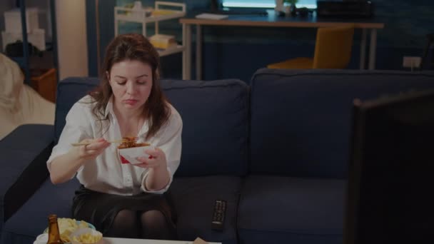 Osoba jedząca azjatycki makaron z pałeczkami na kanapie - Materiał filmowy, wideo