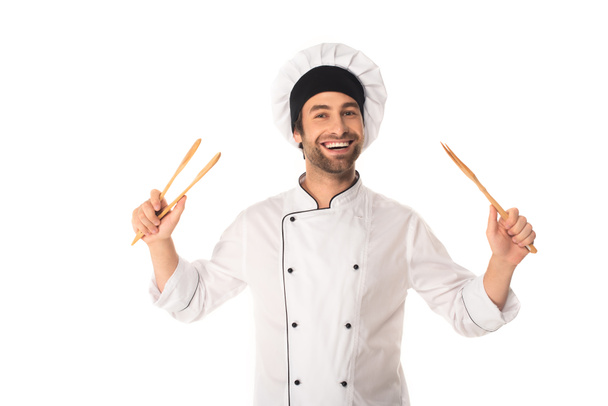 Smiling chef holding wooden tweezers isolated on white  - Fotografie, Obrázek