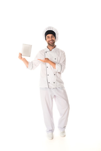 Pozytywny kucharz wskazujący na cyfrową tabletkę na białym tle  - Zdjęcie, obraz