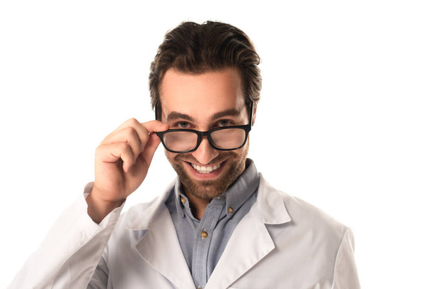 Cheerful doctor holding eyeglasses and looking at camera isolated on white  - Valokuva, kuva