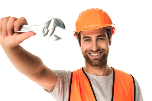 Smiling repairman holding blurred wrench isolated on white  - Φωτογραφία, εικόνα
