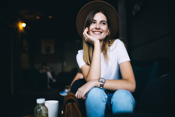 Wesoły radosny kaukaski kobieta hipster dziewczyna zadowolony z wolnego czasu w kawiarni wnętrza odpoczynku, atrakcyjne 20s kobieta w stylowy kapelusz śmiech i zabawy w pomieszczeniach ubrany w cool modnej odzieży - Zdjęcie, obraz