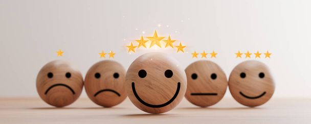 3Dレンダリングによる顧客評価の優れた評価のためのテーブルの上に黄金の5つ星と木製の球上のスマイリーフェイスの印刷画面. - 写真・画像