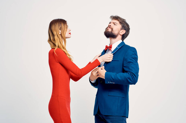赤いドレスの女性の横にスーツを着た男が身振りをする - 写真・画像