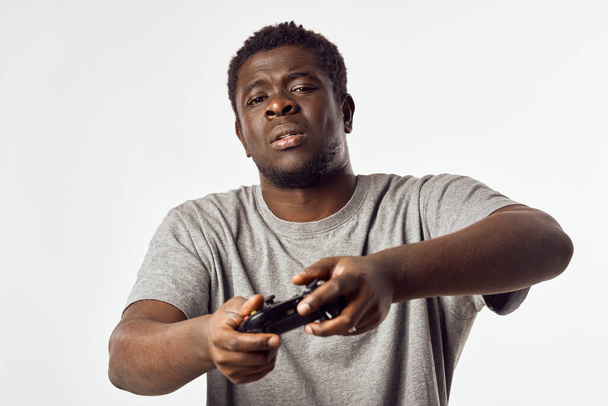 Χαρούμενος άνθρωπος της αφρικανικής εμφάνισης με ένα χειριστήριο στα χέρια του παίζει βιντεοπαιχνίδια - Φωτογραφία, εικόνα