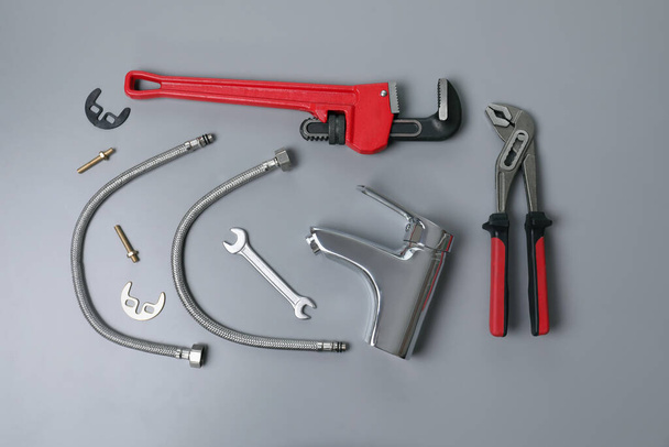 Parts of water tap and wrenches on grey background, flat lay - Φωτογραφία, εικόνα