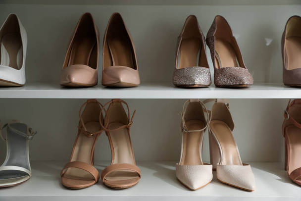Different stylish women's shoes on shelving unit - Valokuva, kuva