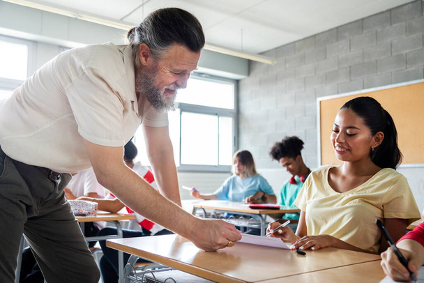 Mature caucasian man teacher helps teenager girl high school student with homework. Copy space. Education concept. - Фото, изображение