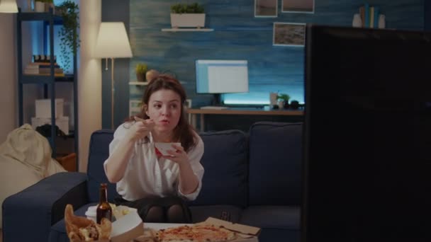Kobieta jedząc chińszczyznę z miejsca na wynos siedzi na kanapie - Materiał filmowy, wideo