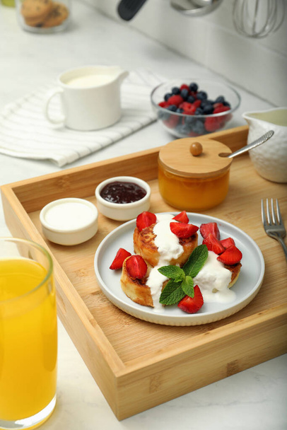 Delicious cottage cheese pancakes with fresh strawberries sour cream and mint served on white countertop - Foto, immagini
