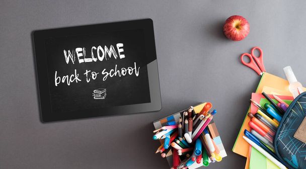 Tablet pc with welcome back to school sign and stationery on the table - Foto, afbeelding