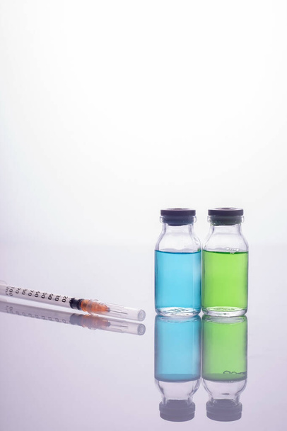 ガラス瓶の中のワクチン注射器。コロナウイルスに対するワクチン - 写真・画像