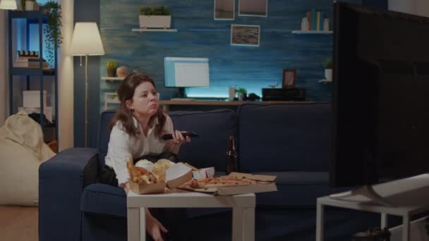 Kobieta relaksująca się na kanapie z jedzeniem na wynos w domu - Materiał filmowy, wideo