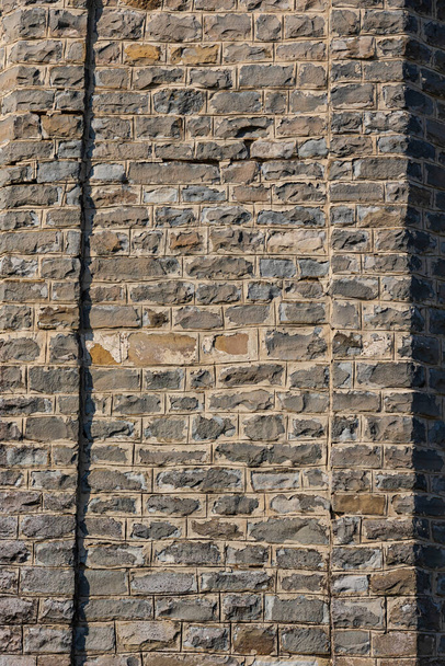 Old gray wall of an ancient castle made of natural stone on a bright sunny day. Flat surface. Hard shadows. Close-up. - Photo, Image