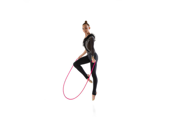 One Caucasian girl, rhythmic gymnastics artist isolated on white studio background. Concept of sport, action, aspiration, education, active lifestyle - Foto, afbeelding